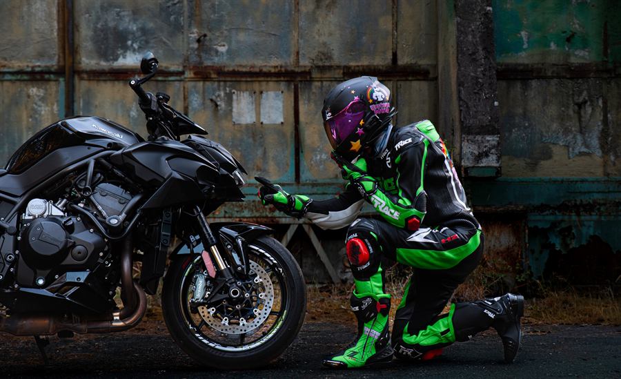 Motorkář klečící vedle Kawasaki