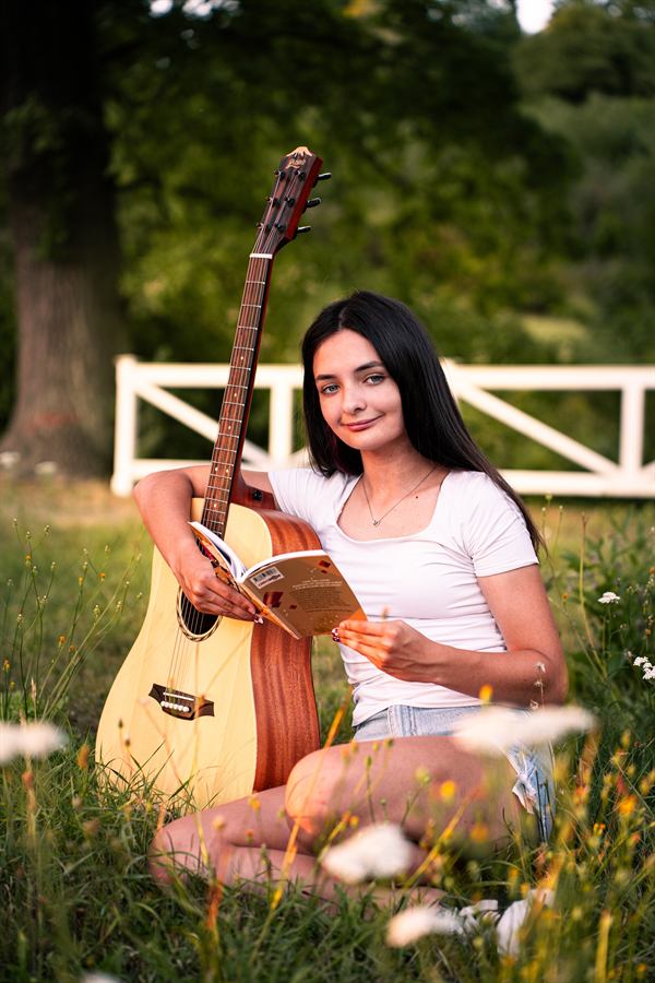 Dívka s kytarou a knihou na louce